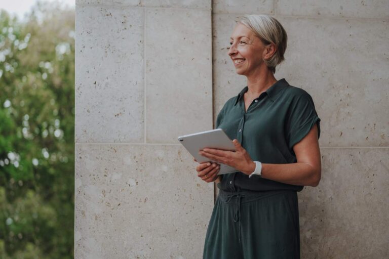 Coaching – Barbara Schemel steht mit Tablet vor einer hellen Wand