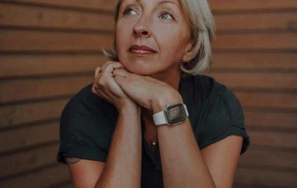 Coaching – Barbara Schemel sitzt nachdenklich vor einer Holzwand