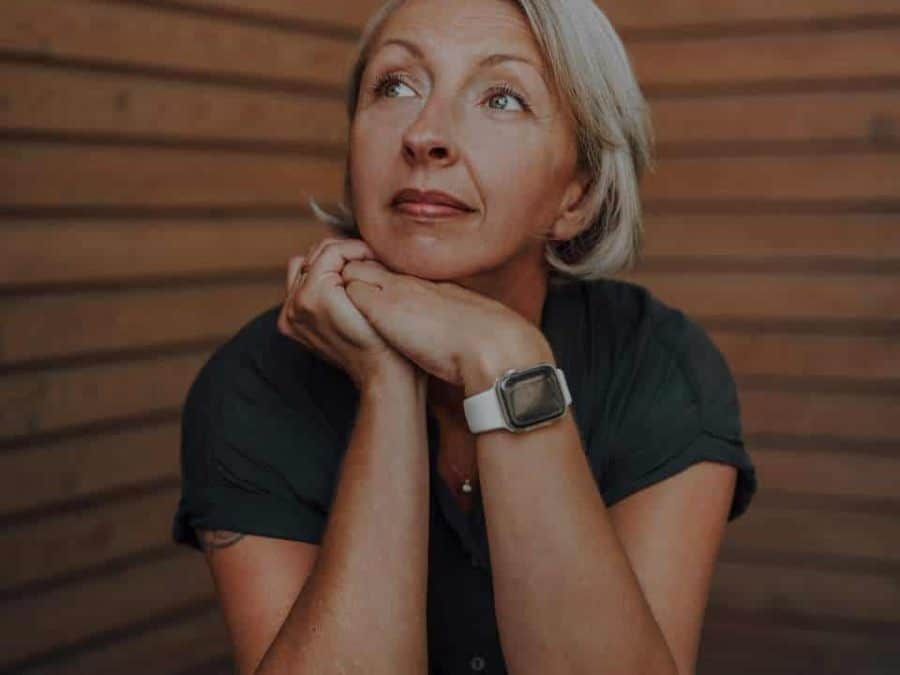 Coaching – Barbara Schemel sitzt nachdenklich vor einer Holzwand