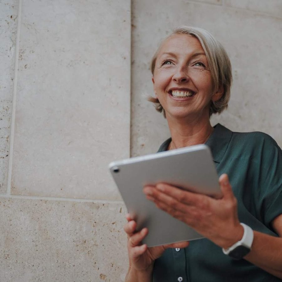 Barbara Schemel lacht und hält ein Tablet in der Hand