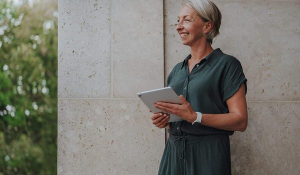 Coaching – Barbara Schemel steht mit Tablet vor einer hellen Wand