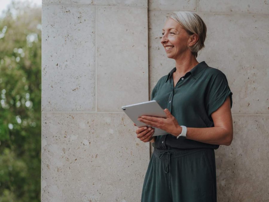 Coaching – Barbara Schemel steht mit Tablet vor einer hellen Wand